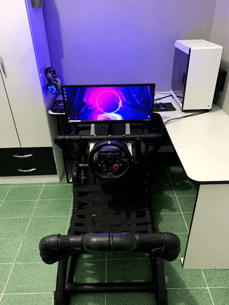The PVC cockpit set up at a desk with an ultrawide monitor and gaming PC